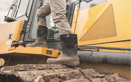 Image features a model stepping up onto a machine while wearing BOGS seamless boots.