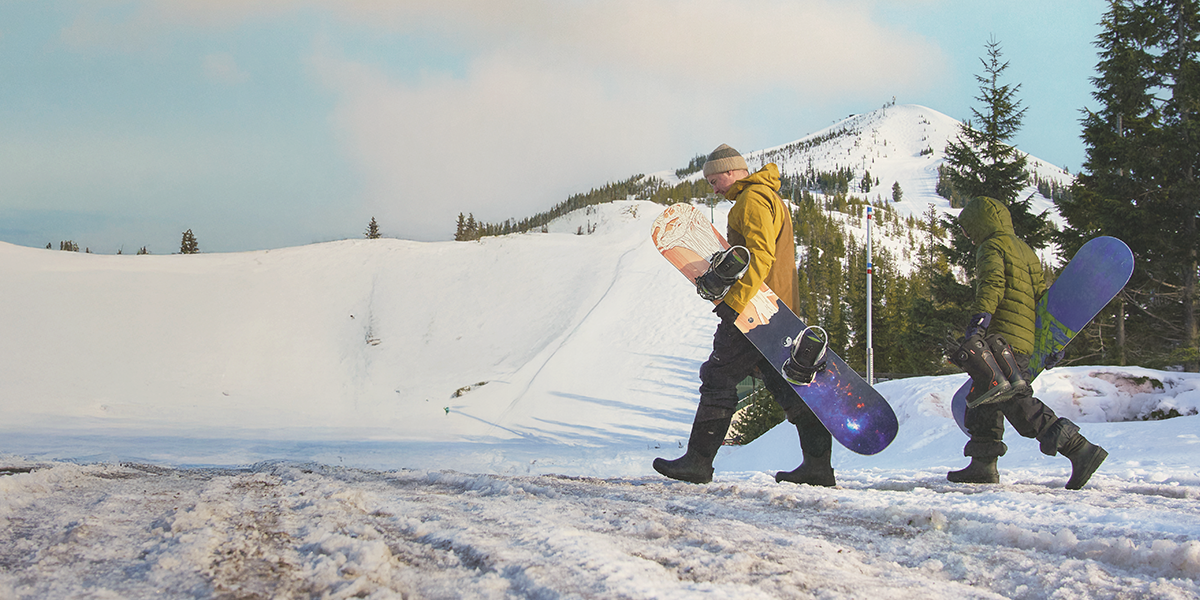 Shop the men's Bozeman II featuring 2 men carrying snowboards.