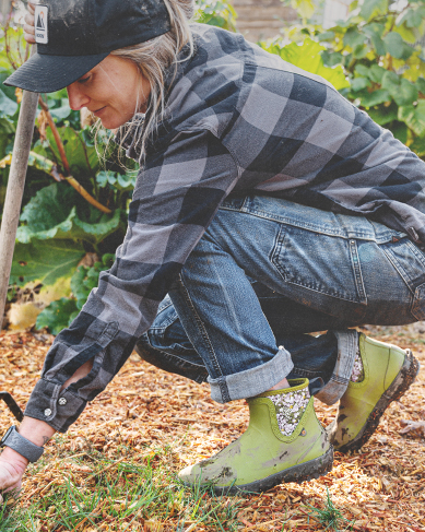 Shop women's garden essentials featuring a woman weeding a garden.