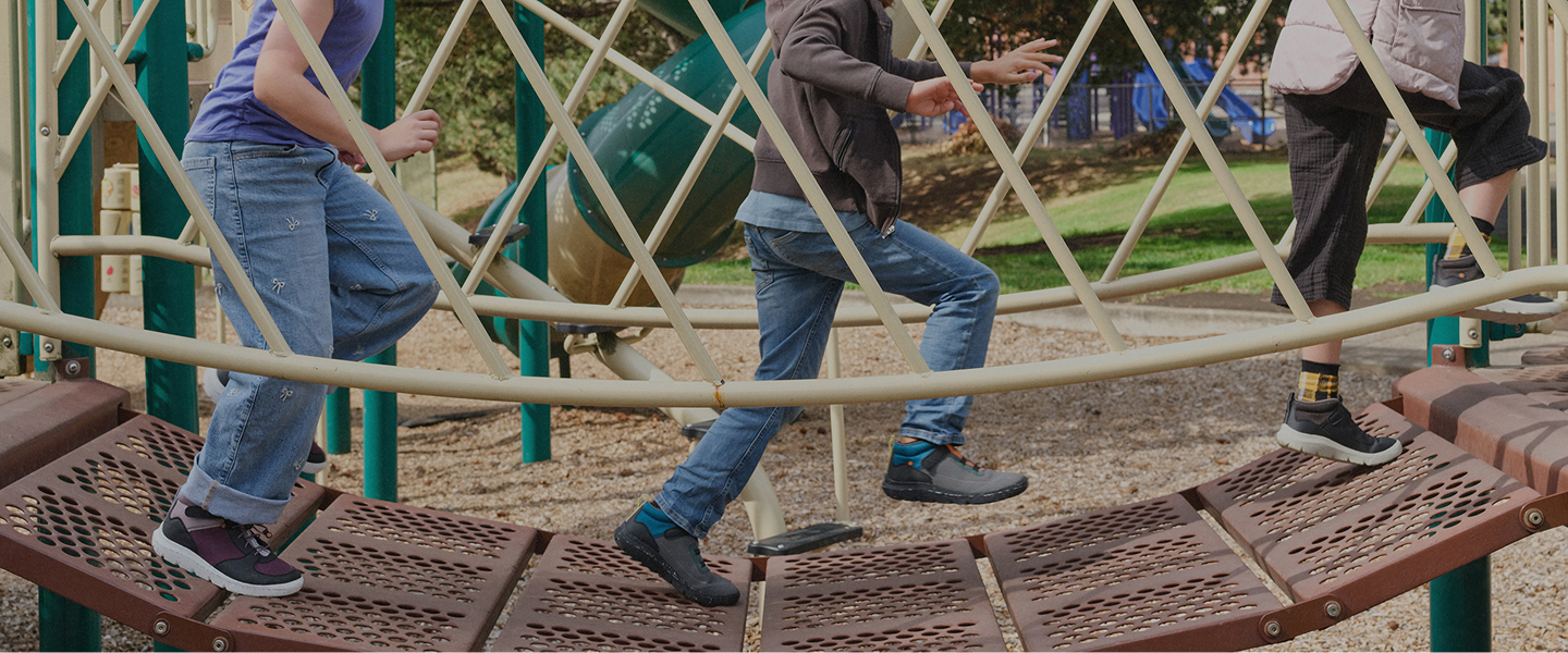 Image features a man in the woods bent down at a campfire wearing BOGS boots.
