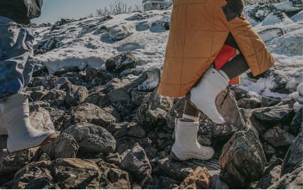 For the Comfort Chaser. Image shows two people in Boga boots walking through rocks and snow. 