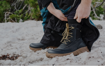 For Men. Image shows a man putting on his Arcata II boots in the snow