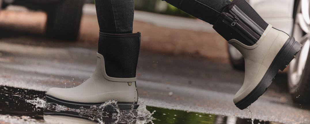 Image features the Hazel Mid Zip in taupe walking through a puddle.