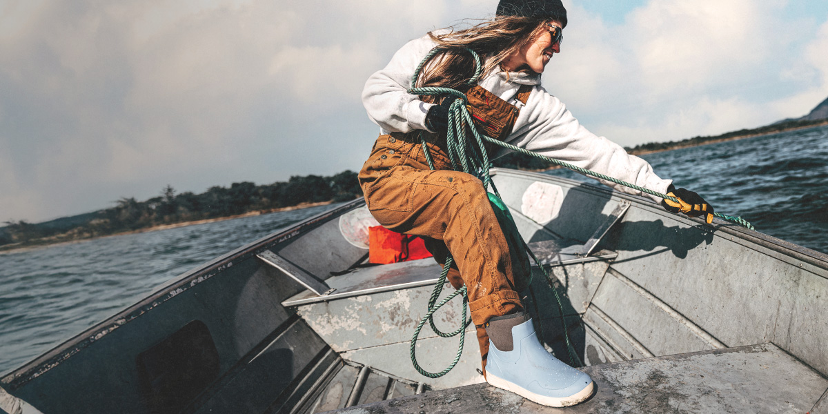 Image features a woman in a fishing boat wearing the Rockaway Seamless Chelsea in blue.