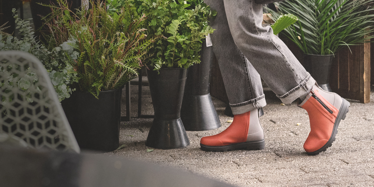 Image features a woman outside a store with potted plants.