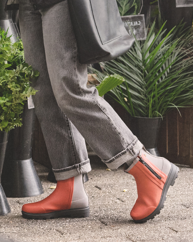 Image features a woman outside a store with potted plants.