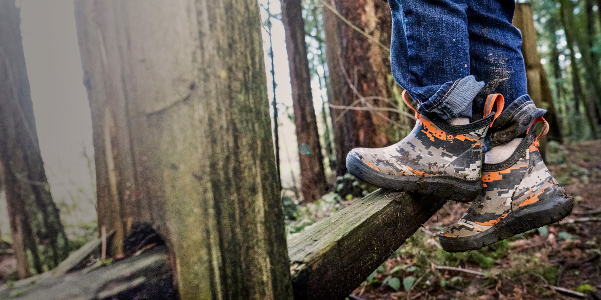 Image features a kid climbing a wooden fence in the woods in the Skyline Chelsea.