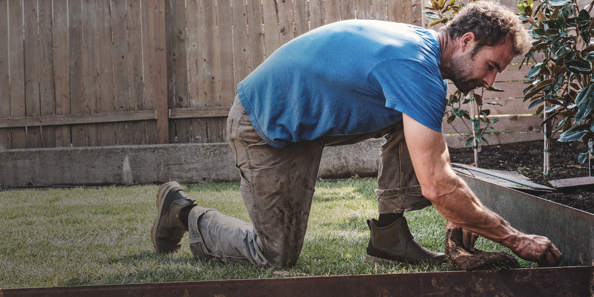 Image features a man working near a raised garden bed in the Spruce Chelsea. 