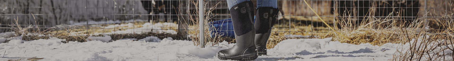 Image features a woman in black muck boots next to an animal pen.