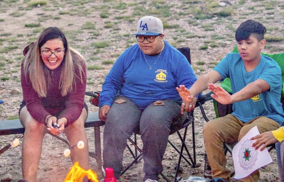 The picture shown are three kids sitting around a camp fire. BOGS is committed to supporting outdoor education efforts to get kids outside to play, learn, and grow.