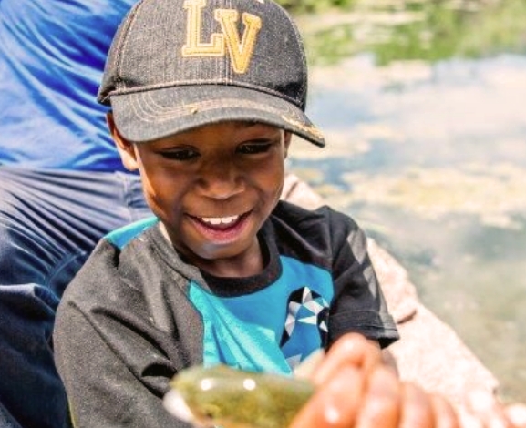 The picture shown a kid holding a fish in his hand. BOGS is committed to supporting outdoor education efforts to get kids outside to play, learn, and grow.